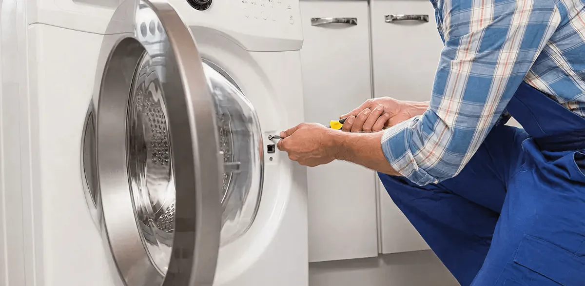Handyman repairing a clothes dryer and checking electrical connections in Jackson, MS