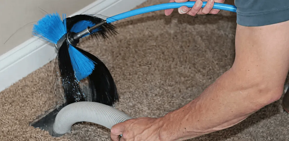 Dryer vent cleaning technician brushing lint from a vent line in Jackson, MS