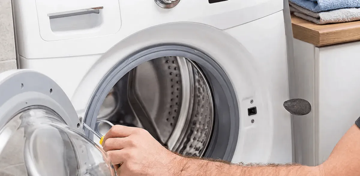 Handyman repairing a front-load washing machine and inspecting the drum in Jackson, MS